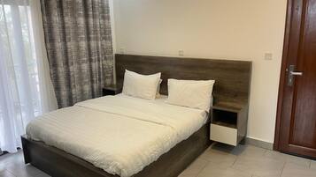 A modern bedroom with a wooden bed frame, white bedding, and a nightstand.