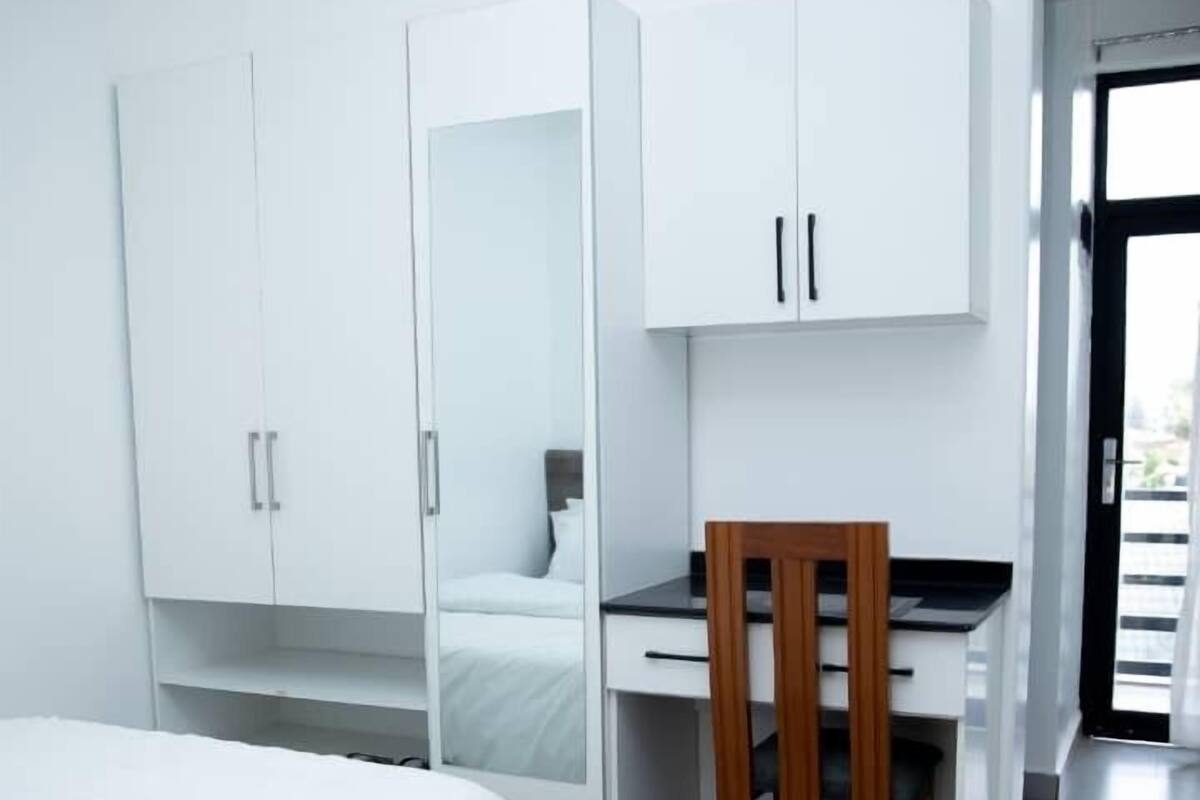 A modern bedroom with a bed, a desk, and a wardrobe.