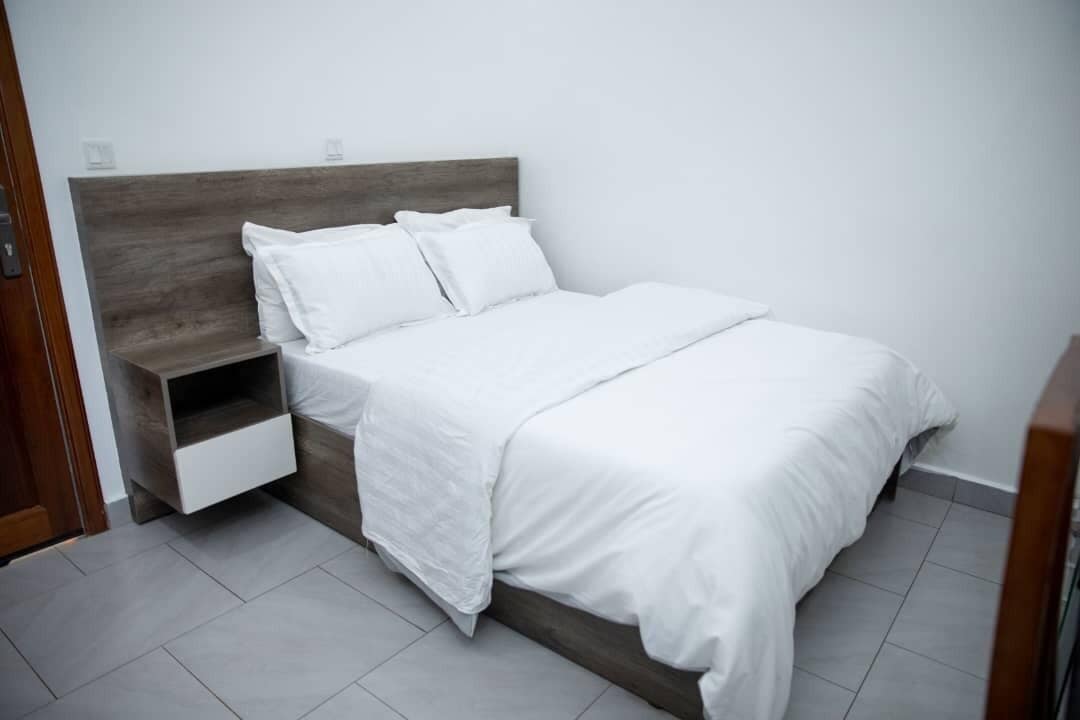 A neatly made bed with white bedding and a wooden headboard.