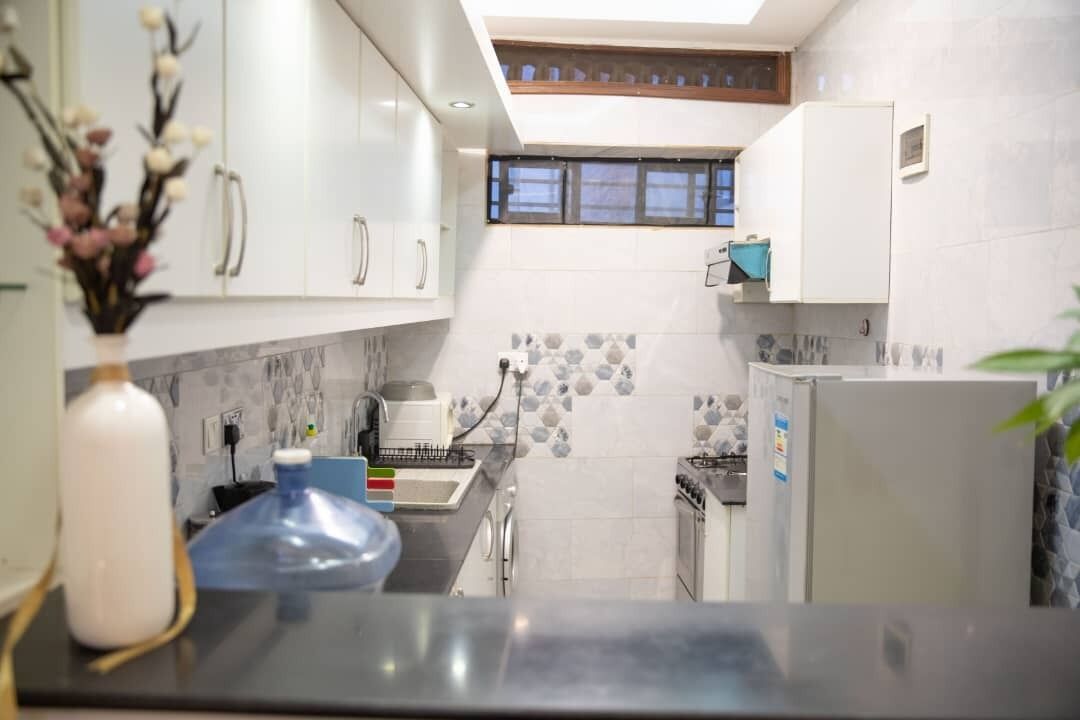 Una cocina moderna con armarios blancos, salpicadero de azulejos y una ventana sobre el fregadero.