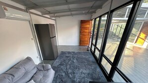 A modern room with a grey sofa, a small table, a rug, a wooden door, and a large window. - #4 - Private Villa 2BR 1000mbps Wi-fi (Ko Pha-ngan)