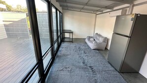 A room with large windows, a grey sofa, a small table, and a refrigerator. - #4 - Private Villa 2BR 1000mbps Wi-fi (Ko Pha-ngan)