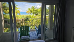 A balcony with a view of the ocean and palm trees. - Stunning 2 bedroom condo at Sunset Cove - Seven Mile beach (George Town)