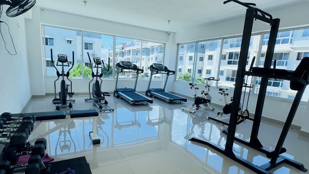 A spacious gym with treadmills, elliptical machines, and free weights.
