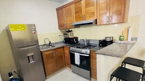 A kitchen with wooden cabinets, a stainless steel refrigerator, a gas stove, and a water dispenser.