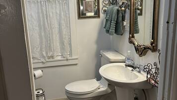 A bathroom with a toilet, sink, decorative mirror, and towel rack.