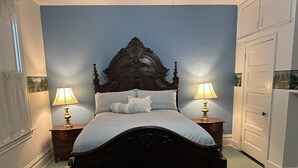 A bedroom with a dark wooden bed, two bedside tables with lamps, a white door, and a blue wall. - Charming 4-bedroom family friendly house in Monongahela. Make yourself at home! (Monongahela)