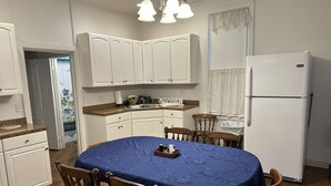 A kitchen with white cabinets, a blue table, and a white refrigerator. - Charming 4-bedroom family friendly house in Monongahela. Make yourself at home! (Monongahela)