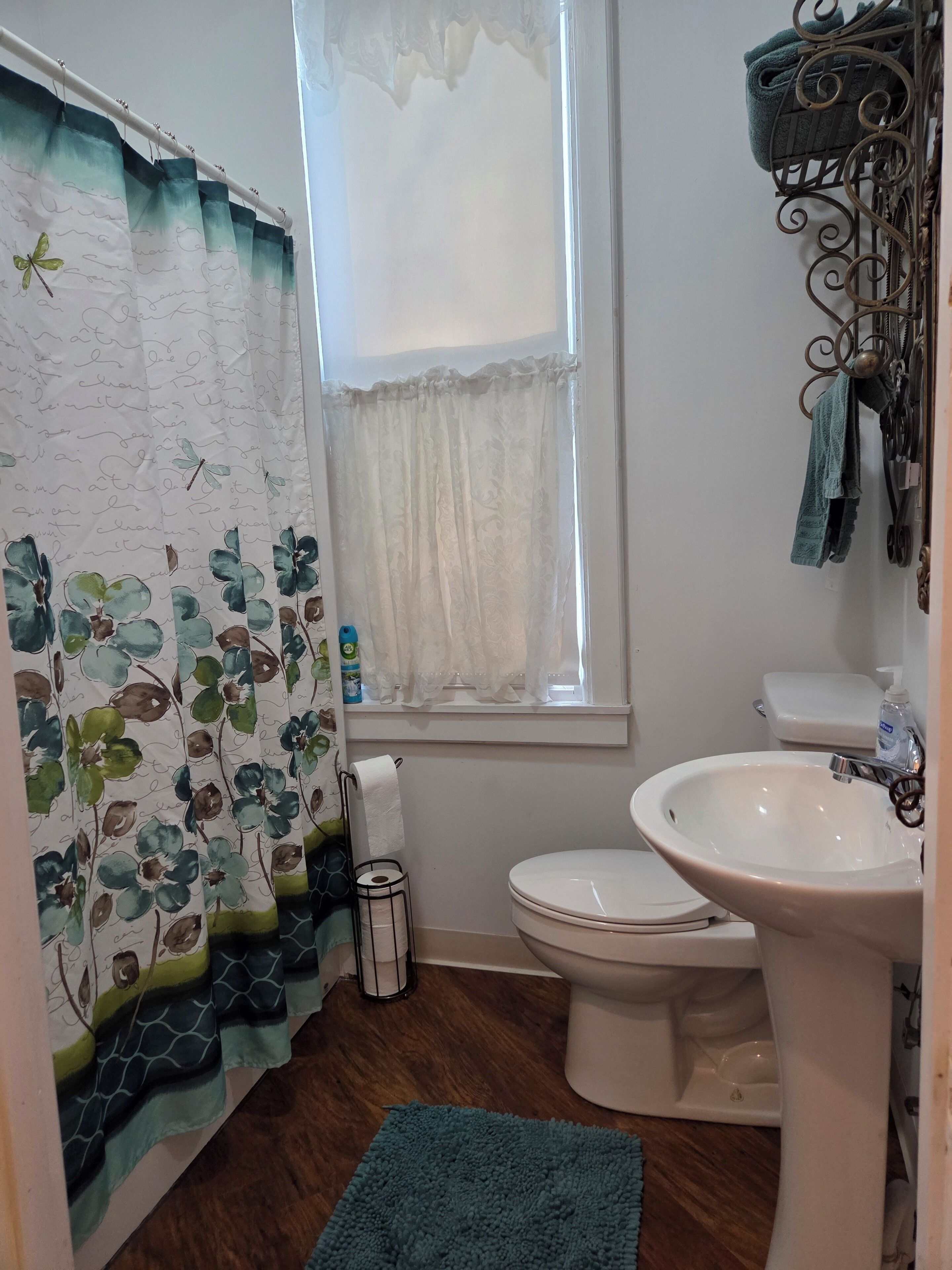 Een badkamer met toilet, wastafel en raam met gordijn.