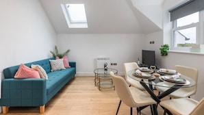 A modern living room with a teal sofa, a glass dining table, and a small TV. - F8  Leatherhea (Leatherhead)