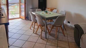 Un comedor con mesa y sillas, un refrigerador y una zona de cocina.