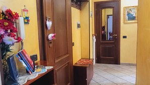 Un pasillo con una puerta de madera, un pequeño banco y suelo de baldosas.