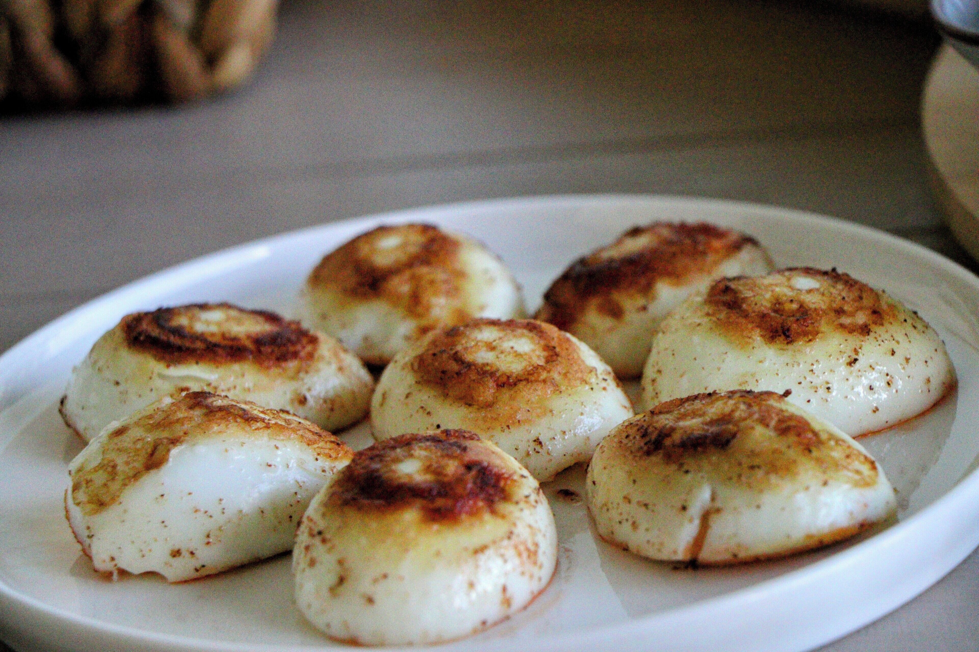A plate of round, golden-brown dumplings on a white plate.