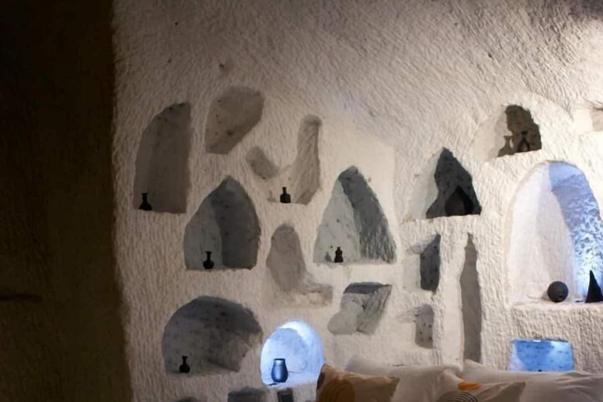 Ein Schlafzimmer mit Steinwand, einem Bett und einem kleinen Fenster.