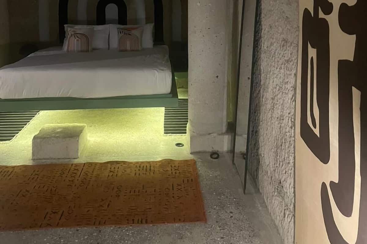 Ein Zimmer mit einem Bett, einem gemusterten Teppich und einer Wand mit einem großen, abstrakten Design.