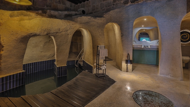 A spa area with a wooden deck, stone walls, and a sink. - EKA CAVE MAISON (Ürgüp)