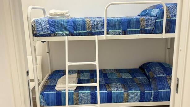 Un lit superposé avec une literie à motifs bleus et une structure en métal blanc.