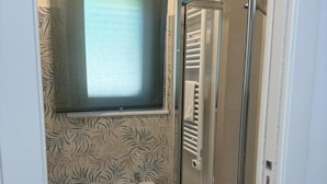 Ein Badezimmer mit einem Bidet, einem Waschbecken, einem Fenster und einer Duschkabine aus Glas.