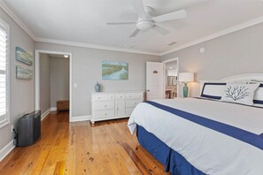 Relax in a spacious room with a large bed, dresser, and ceiling fan for a comfortable stay.