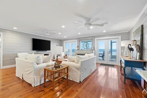 Relax in this spacious living area with a high ceiling, featuring a large flat-screen TV, comfortable sofas, and a fireplace.