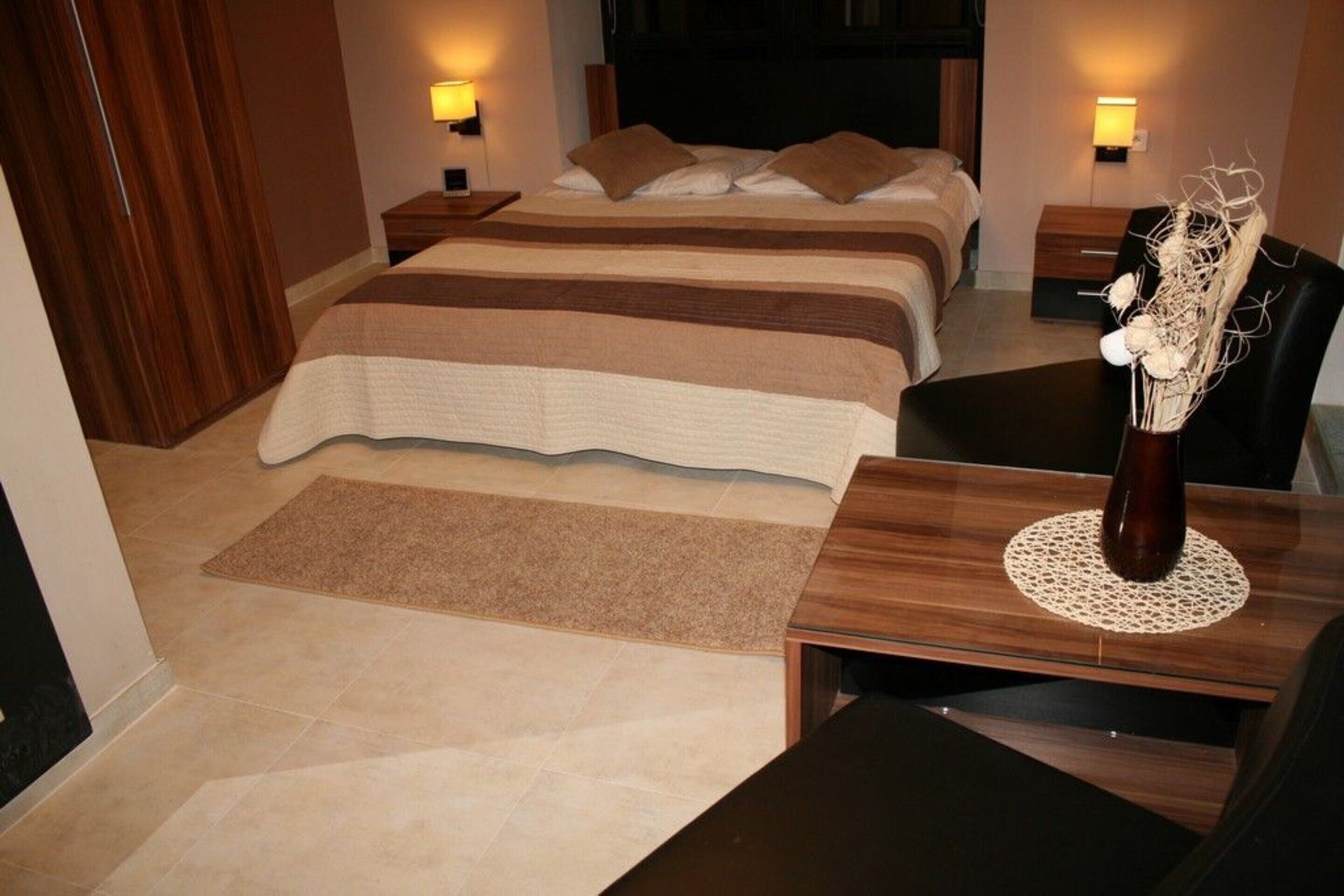 Een hotelkamer met een groot bed, twee nachtkastjes, een bureau en een stoel.