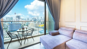 Een moderne woonkamer met een ruim balkon, een bank en een eettafel met stoelen.