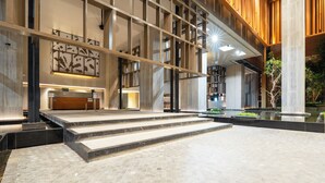 Een modern gebouw met een receptiebalie, een trap naar de bovenverdieping en een binnentuin met een fontein.