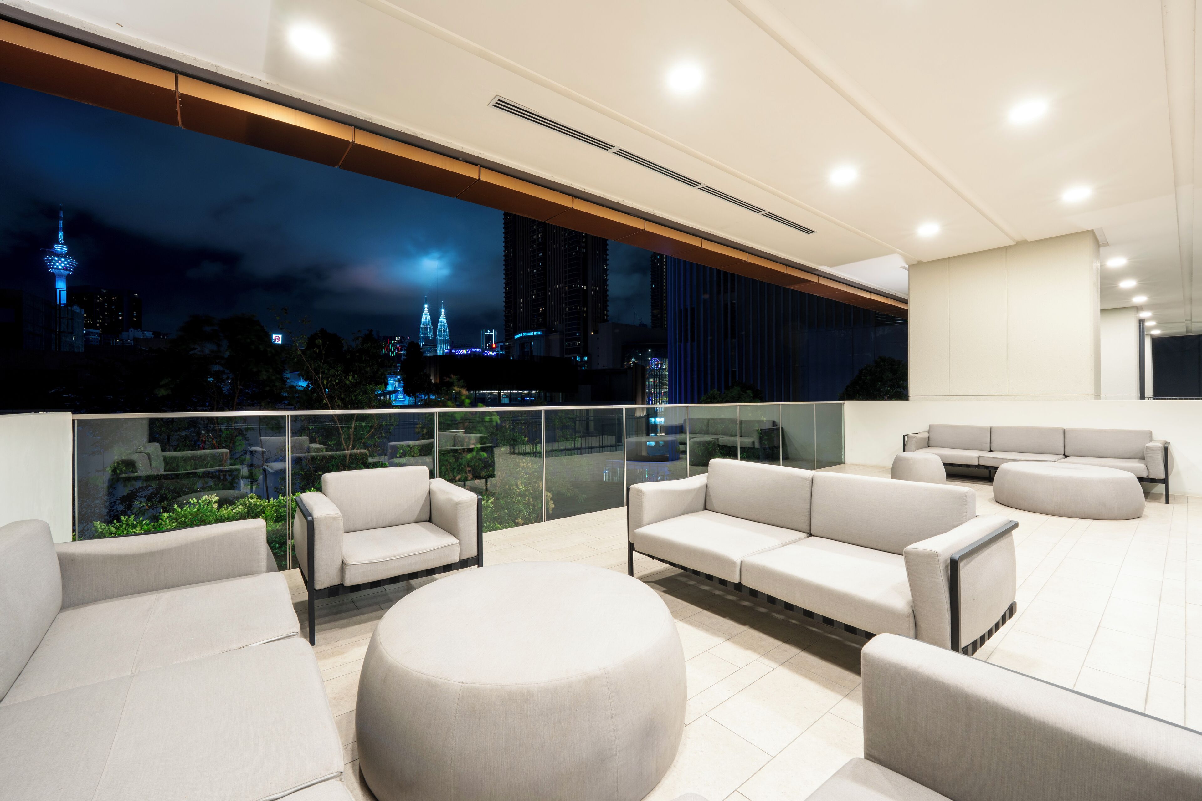 Een moderne lounge met een groot raam met uitzicht op een stadsgezicht 's nachts.