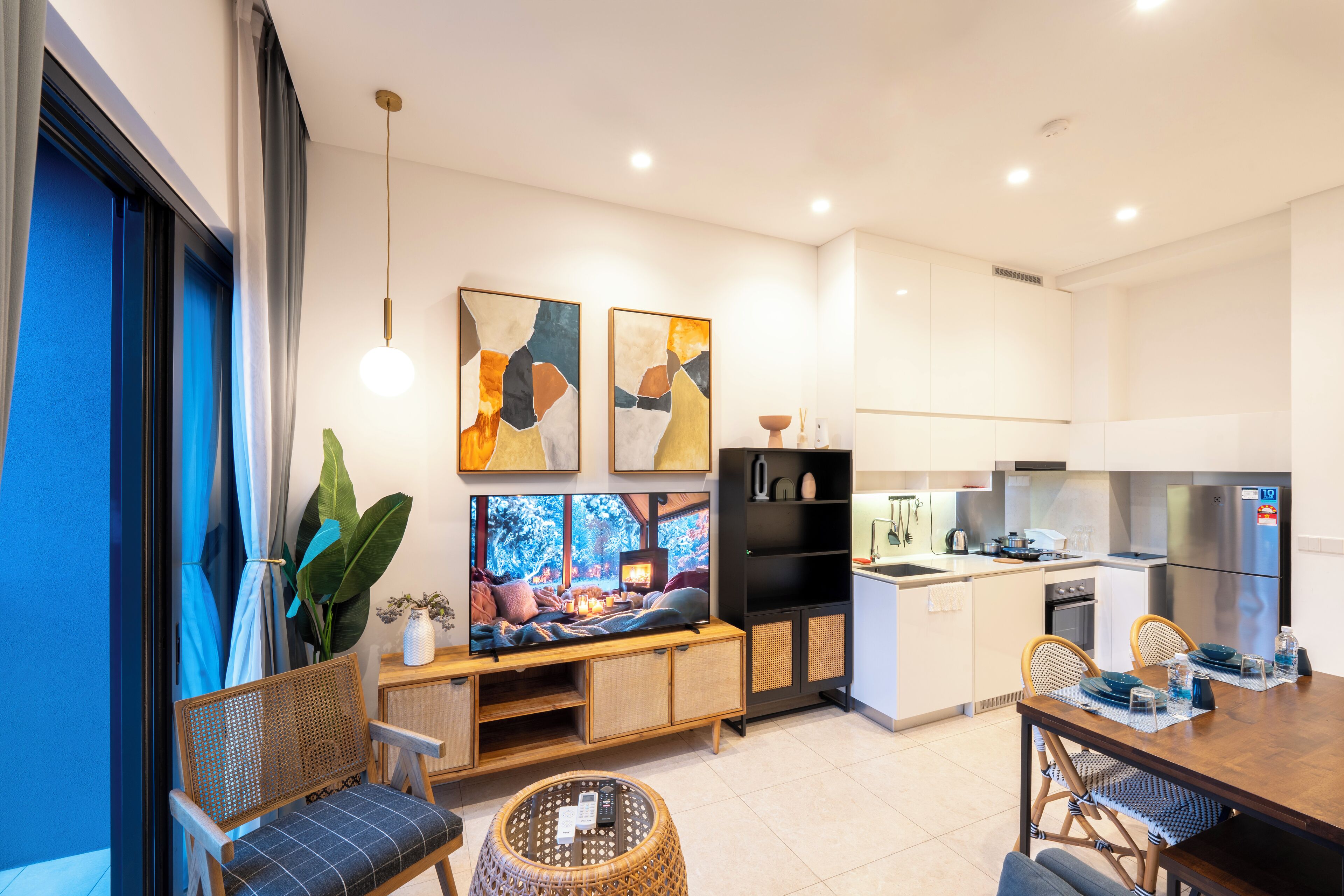 A modern kitchen with a built-in oven, a refrigerator, and a dining area with a wooden table and chairs.