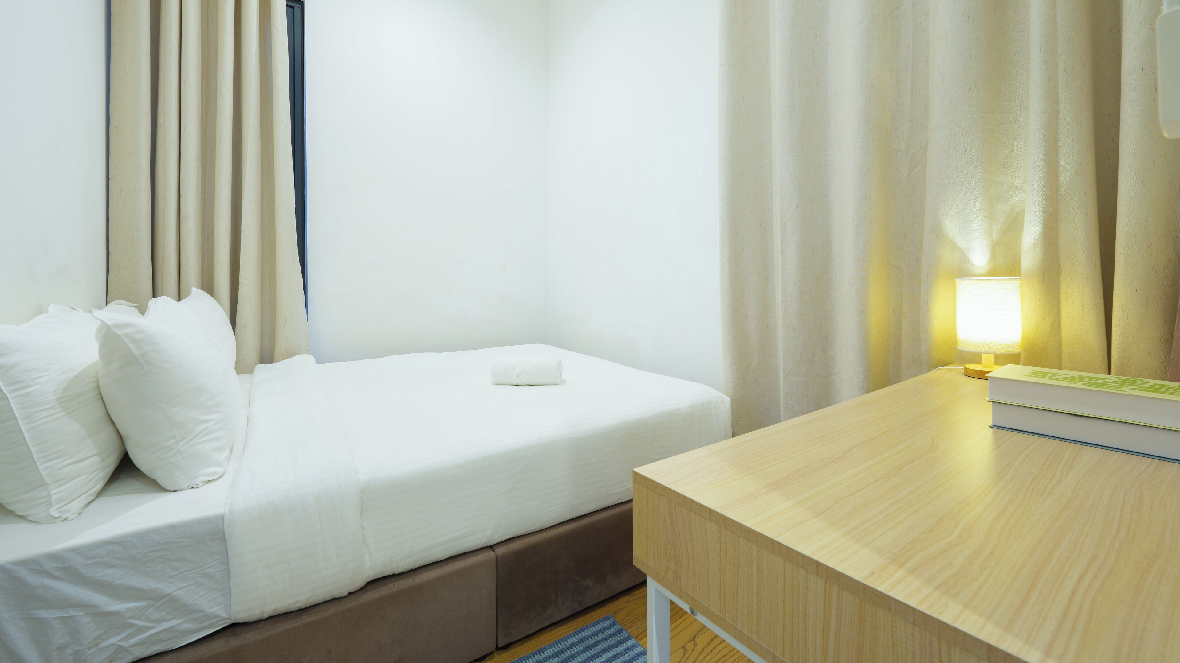 Una habitación de hotel con cama, una mesita de noche con lámpara y una ventana con cortinas.