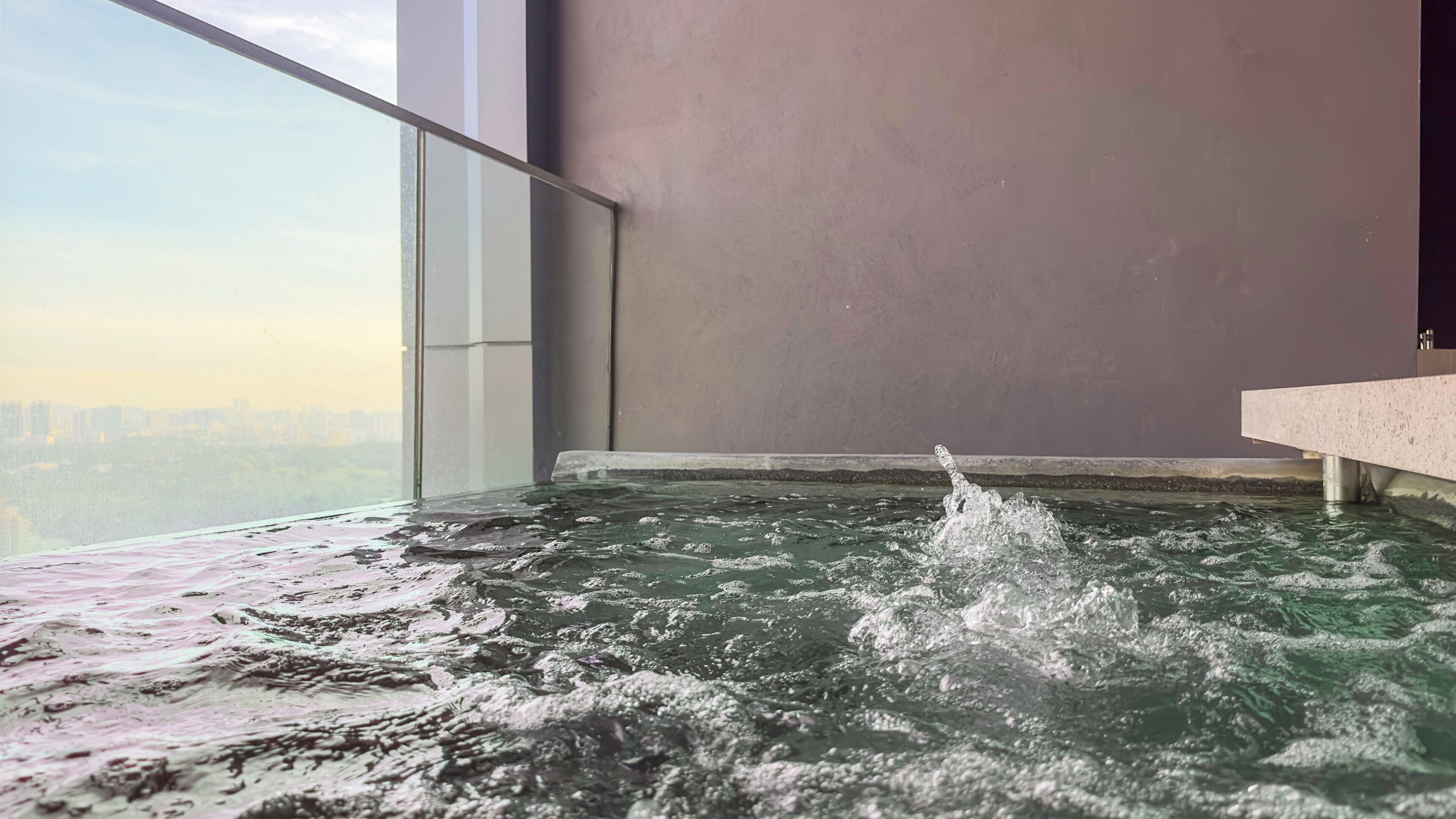 A hot tub with a city view, a large window, and a modern interior design.