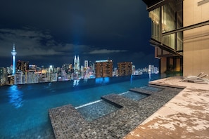 A rooftop infinity pool with a city skyline view, including the Petronas Towers, and a modern building with a glass facade. - Harmony Luxury Suites At Lucentia BBCC (Kuala Lumpur)