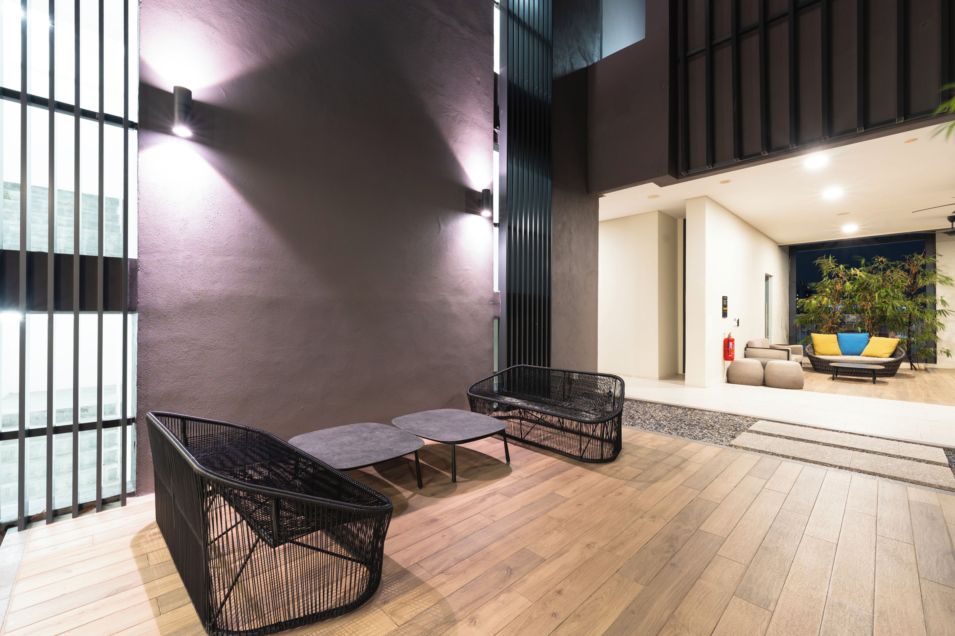 A modern interior with a seating area featuring black wicker furniture and a wooden floor.