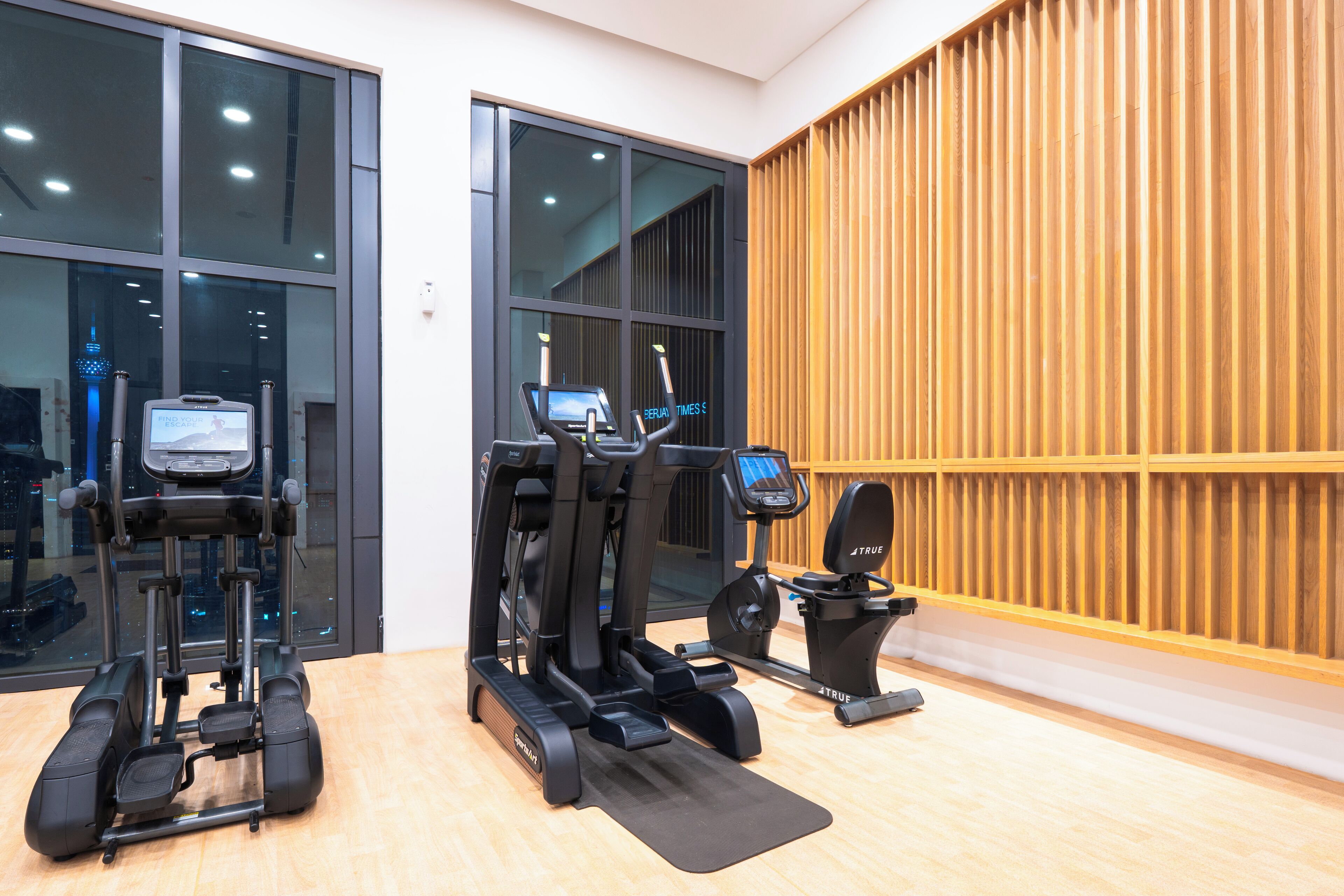 Un gimnasio con cintas de correr, elíptica y bicicleta estática.