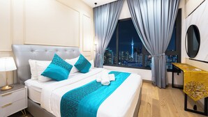 Een moderne hotelkamer met een groot bed, een ’s nachts zicht op de stad en een klein tafeltje met een gele tafelkleed.
