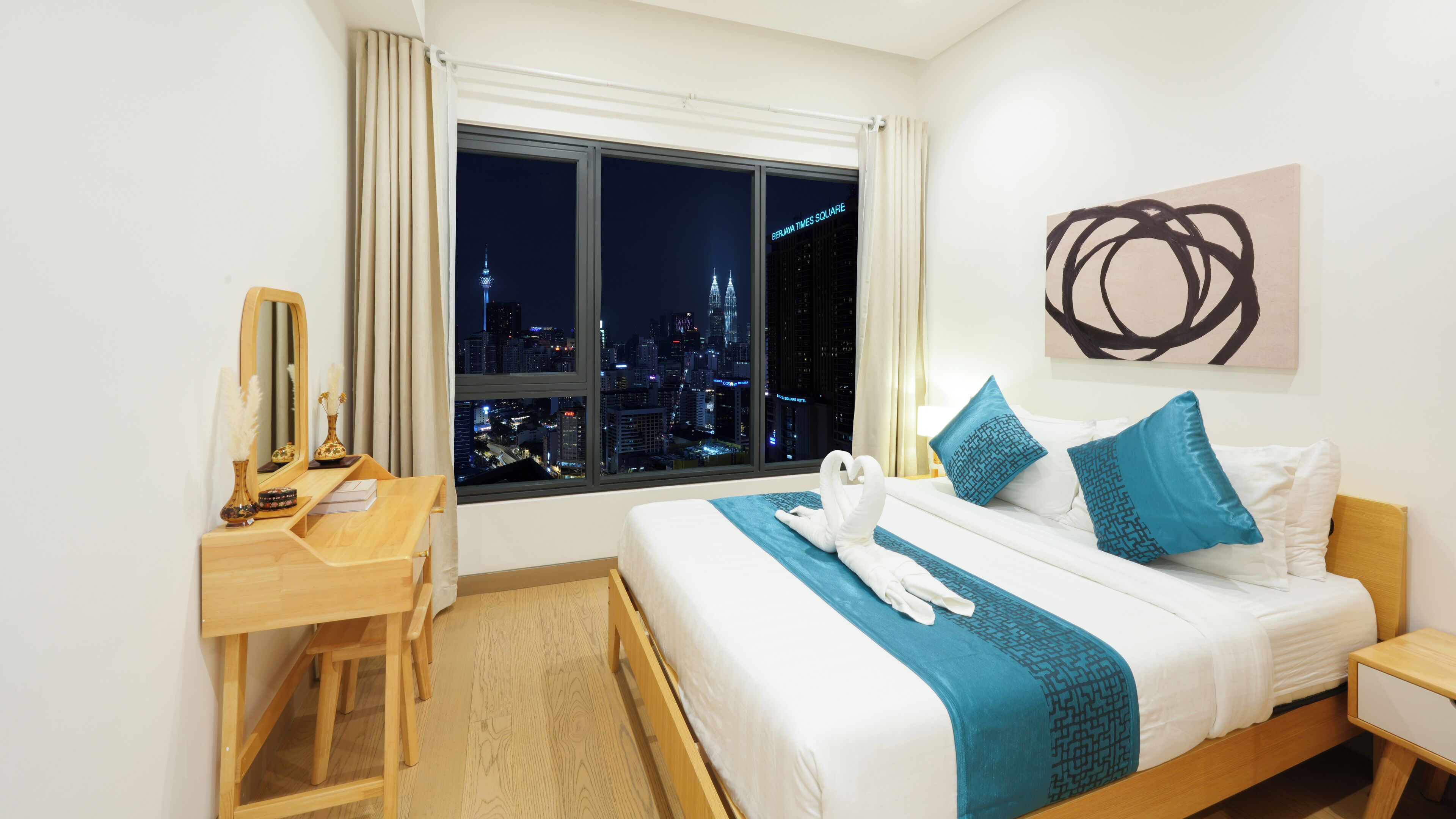 A hotel room with a bed, a desk, a chair, a window with a city view, and a painting on the wall.