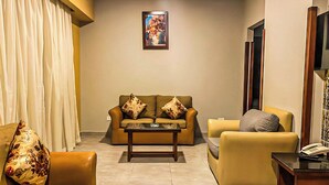 A living room with a sofa, armchairs, a coffee table, and a painting on the wall. - Luxury Apartment 3BR & Full Sea View (Marsa Matrouh)