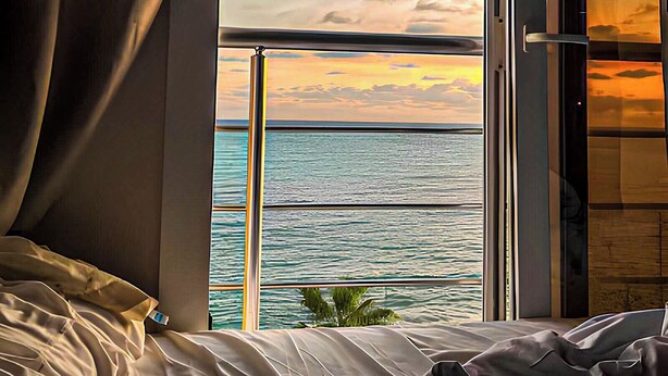 A room with a bed, a window with curtains, and a view of the sea and sky. - Luxury Apartment 3BR & Full Sea View (Marsa Matrouh)