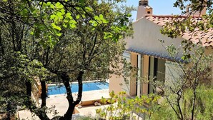 A pool area with a view of a building with a tiled roof and a chimney. - Charming family villa in Tourtour. 40 minutes from the Côte d'Azur. (Tourtour)