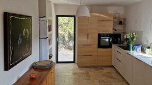 A modern kitchen with a large window, wooden cabinets, and a countertop with a vase of flowers. - Charming family villa in Tourtour. 40 minutes from the Côte d'Azur. (Tourtour)