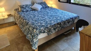 A bedroom with a bed, a bedside table, a lamp, and a window. - Charming family villa in Tourtour. 40 minutes from the Côte d'Azur. (Tourtour)