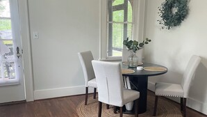 A dining area with a round table, four chairs, a woven rug, a vase with greenery, and a wreath on the wall. - Welcome to Augusta. This beautiful and home has lots of Southern Charm. (Augusta)