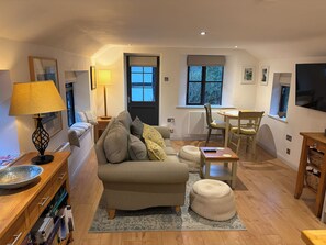 A cozy living room with a sofa, ottoman, and a dining area with a table and chairs.