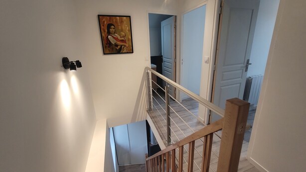 A staircase with a wooden handrail and a painting on the wall. - Charming triplex near Disney  (Quincy-Voisins)