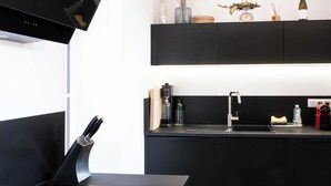 Een moderne keuken met een zwart aanrecht, roestvrijstalen apparatuur en een houten plafond.