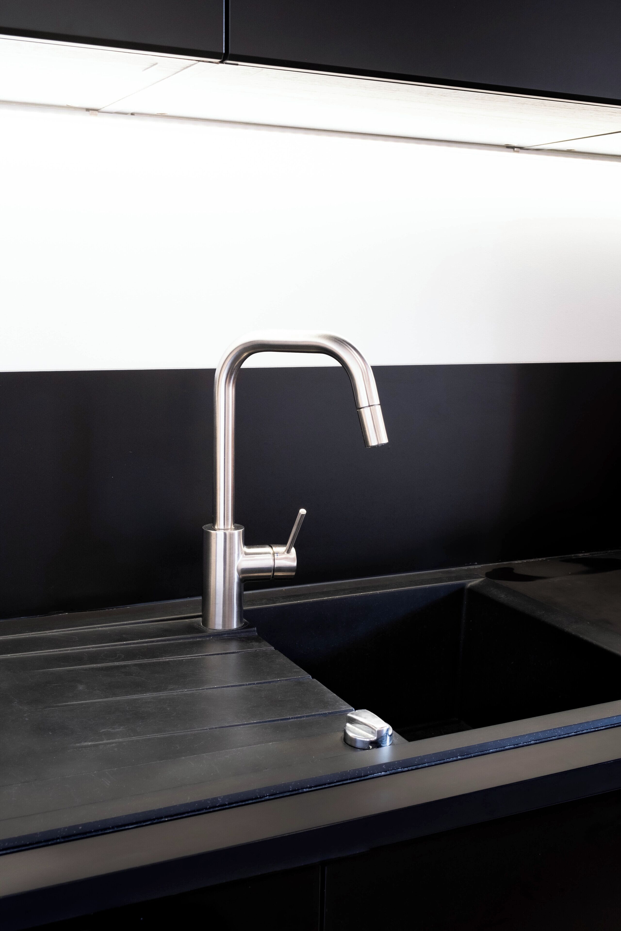 A modern kitchen with a stainless steel faucet and a black countertop.