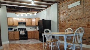 A kitchen with wooden cabinets, a black refrigerator, and a dining table with white chairs.