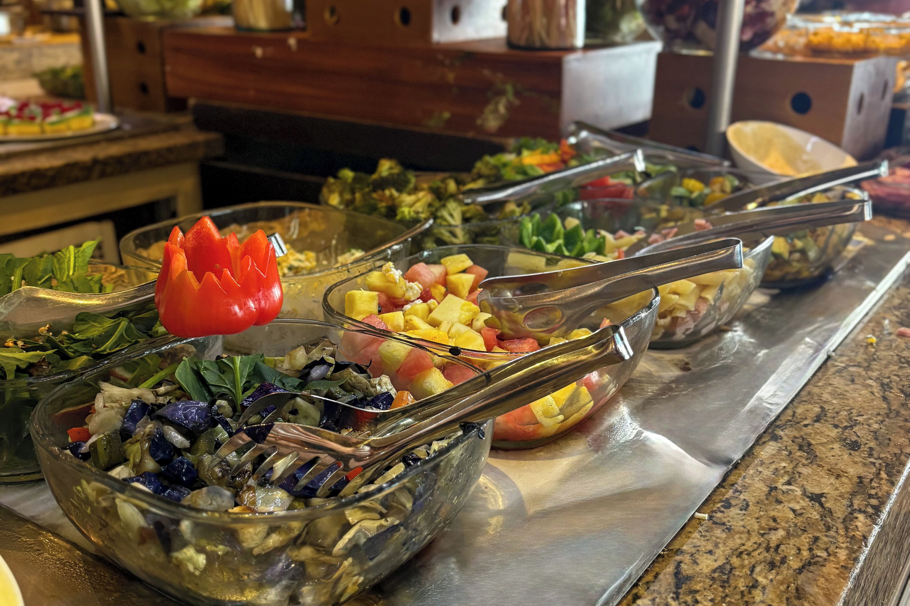 A buffet with various dishes including salads, fruits, and vegetables.