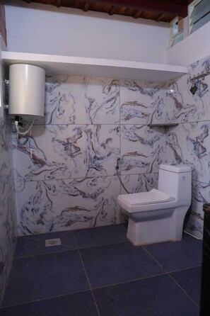 A bathroom with marble-patterned walls, a white toilet, and a wall-mounted water heater.