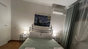Cama bem arrumada com duas almofadas, um quadro acima e duas mesas de cabeceira com abajures.